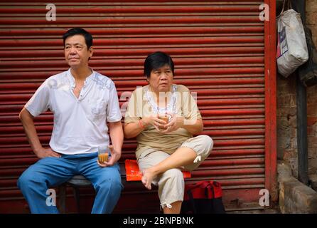 A chinese couple sitting by the roadside drinking tea. Stock Photo