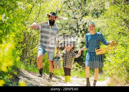 Farmars couple with son enjoy spring nature and take care about her plants. A pair with child of farms working in the garden Stock Photo