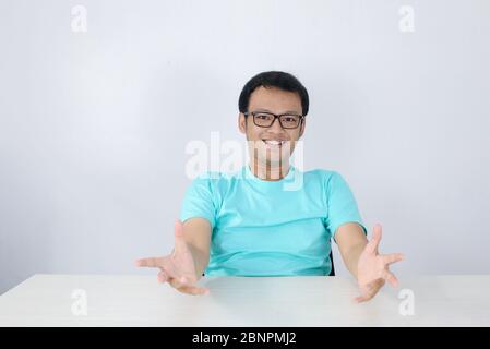 Young asian man looking at the camera smiling with open arms for hug. Cheerful expression embracing happiness. Stock Photo