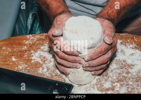 Close-up of man hands kneading bread dough on a cutting board. Stock Photo