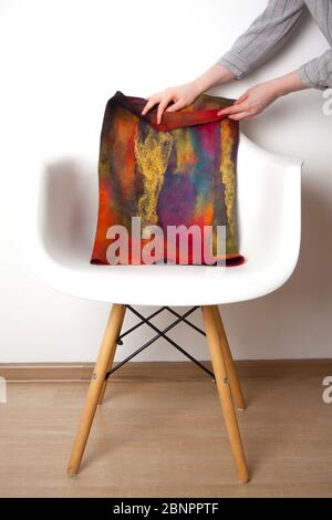 Bright blue-violet silk wool scarf made hand-made by an unidentified woman designer lies on light chair on white background. Concept of unique natural Stock Photo