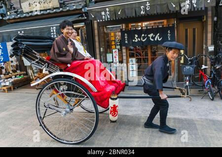 Japan, Honshu, Tokyo, Asakusa, Couple Riding in Rickshaw Stock Photo