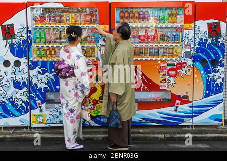 Japan, Honshu, Tokyo, Asakusa, Couple Dressed in Traditional Japanese Clothing Buying Drinks from Street Vending Machine Stock Photo