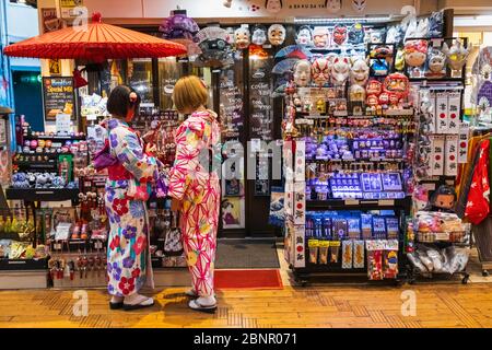 Japan, Honshu, Tokyo, Asakusa, Two Woman Dressed in Kimono in front of  Souvenir Shop Stock Photo