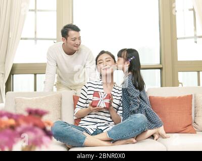 little asian gilr daughter kissing mother on the cheek after giving a present Stock Photo