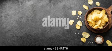 Homemade potato chips in bowl. Crispy potato chips on black background, banner, copy space. Stock Photo