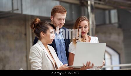group of three , two women and one man, looking at content on laptop Stock Photo