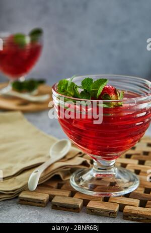 Jelly with strawberries in a glass on a wooden board, against a background of concrete. Selective focus Stock Photo