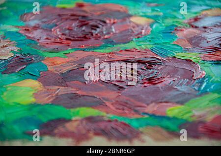 Closeup of oil painting strokes made by palette knife. Vibrant color red and green abstract background with textured rippled surface and blurred vigne Stock Photo