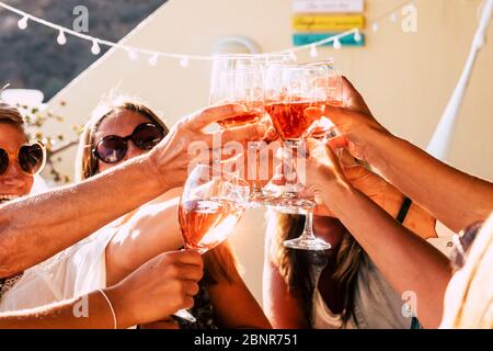 Group of happy people toasting  together with cups of red wine under the sun light in a sunny day - outdoor leisure activity for women having fun with drinks - wine and winery concept Stock Photo