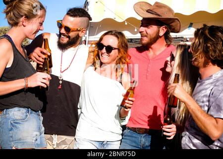 Group of alternative young caucasian people have fun and enjoy together with friendship and smiles and beer bottles - youthful lifestyle for different life in the countryside and far from urban technology Stock Photo