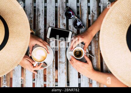Above vetical view of couple of caucasian people women friends together taking italian coffee and cappuccino at the bar - concept of friendship and alternative lifestyle lgbt - wooden trendy table outdoor Stock Photo
