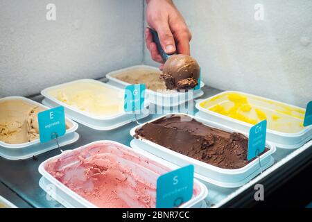 Male hand scooping chocolate ice cream in an ice cream shop Stock Photo