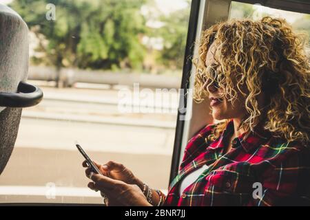 People and travel with technology - adult caucasian woman traveler use mobile phone and connection inside the bus or train - transport concept Stock Photo