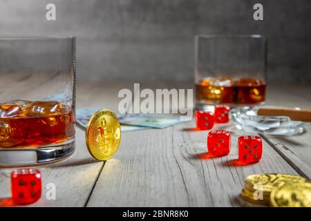 Rustic wooden table. Two glasses of whiskey with ice cubes and a cigar in an ashtray. Dice and dollar bills. Few bitcoin coins Stock Photo