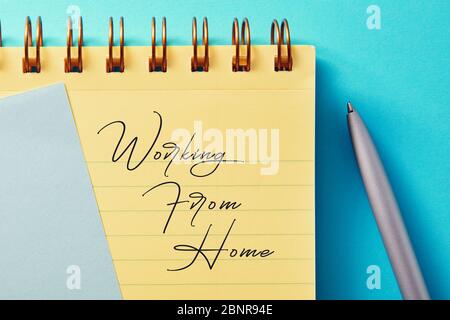 Yellow notepad and pencil with working from home message on blue background. Work from home during coronavirus quarantine or home isolation concept. Stock Photo
