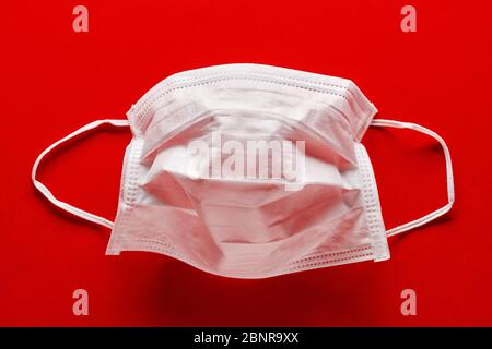 Medical or surgical mask for protection against virus diseases on red background. COVID-19 or corona virus protection. Stock Photo