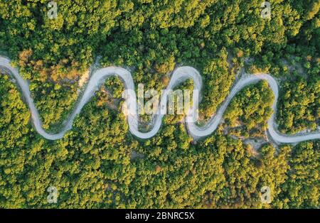 Road trip, car going through a curve road. Aerial point of view Stock Photo