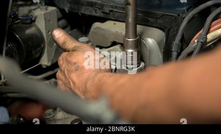 Auto mechanic working on car engine in mechanics garage. Stock Photo