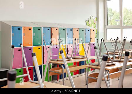Close up of modern empty classroom with colorful lockers and raised chairs on the tables - back to school Stock Photo