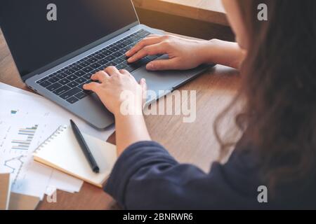 Closeup image of woman using and typing on laptop while working in office Stock Photo
