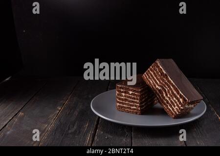 Two large chocolate cakes on a black plate. Dark mood. Front view. Stock Photo