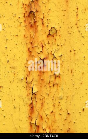 Wall with yellow peeling paint with cracks and rust. Speckles on a painted surface. Aging weathered texture. Stock Photo