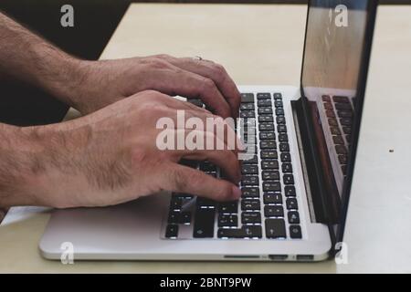 Work from home hands typing on computer for social distancing and COVID-19 (Coronavirus) concepts. Stock Photo