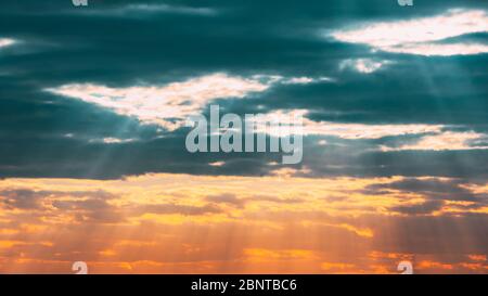 Sun Rays Shining Through Cloudy Sky With Fluffy Clouds. Sunset Sky During Rain. Stock Photo