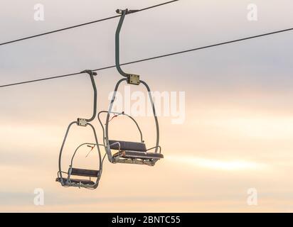 ski lift with seats going over the snow mountain in ski resort when sunset. Stock Photo