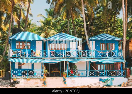 Canacona, Goa, India - February 16, 2020: Famous Painted Guest Houses On Palolem Beach Against Background Of Tall Palm Trees In Sunny Day.