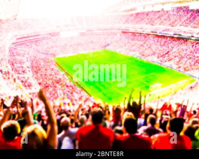 Football- soccer fans cheer their team and celebrate goal in full stadium with open air  with bright lighting beam     -blurred. Stock Photo