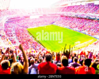 Football- soccer fans cheer their team and celebrate goal in full stadium with open air  with bright lighting beam     -blurred. Stock Photo