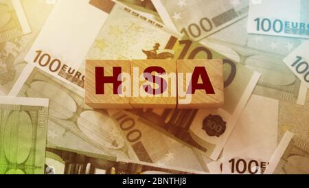 Wooden blocks with the word HSA standing for Health savings account put on 100 Euro bills. Healthcare, life insurance, medical expenses concept Stock Photo