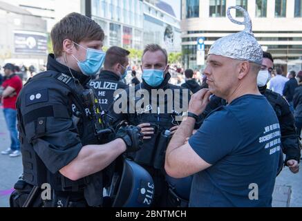 16 May 2020, Hessen, Frankfurt/Main: Policemen gave a man with an aluminium hat on his head a reprimand after he tried to interfere with the participants of a rally against a right-wing demonstration. Photo: Boris Roessler/dpa Stock Photo