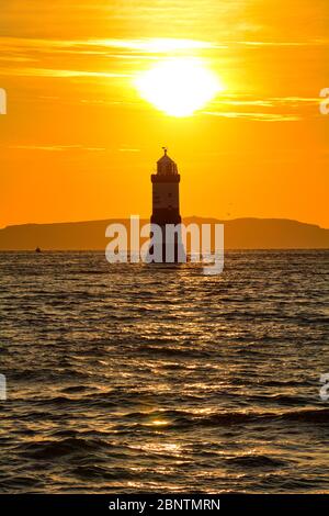 Sunrise over Trwyn Du lighthouse at Penmon on Anglesey in North Wales Stock Photo