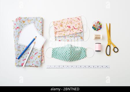 DIY Cotton face mask composition with fabric, pattern, threads, scissors, and sewing accessories on white background, flat lay Stock Photo