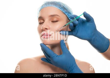 Portrait of young Caucasian woman getting cosmetic injection of botox, isolated over white background. Stock Photo