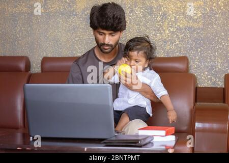 Young father with his little son working on laptop at home - Concept of work form home or wfh reality, People Lifestyles and technology Stock Photo