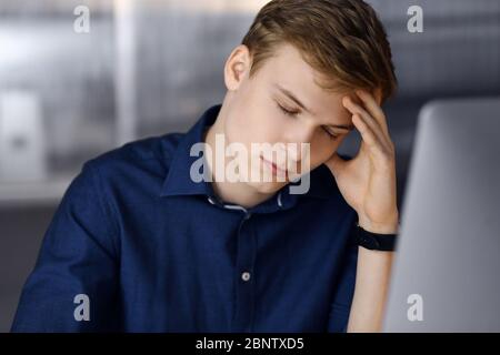 Young blond businessman feeling stress at workplace in office. Startup business means working hard and out of time for success achievement Stock Photo