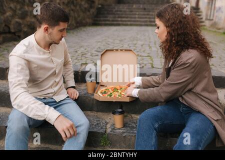 Couple grab slices of pizza from box at the outdoor. Man and woman hands taking pizza. Vegan pizza with fresh tomatoes basil and broccoli. Lactose and Stock Photo