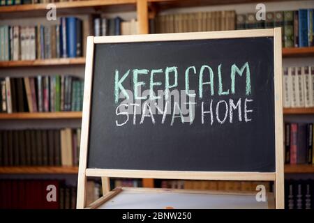 Inscription keep calm stay at home. Outbreak Warning. written white chalk on blackboard in connection with epidemic of coronavirus worldwide. Covid 19 Stock Photo