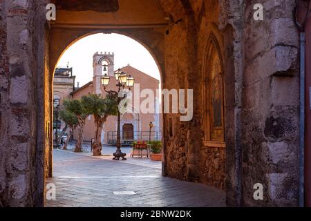 Empty Corso Umberto street and Piazza 9 Aprile square in rainy morning, view from Porta di Mezzo, Old Clock Tower and gateway, Taormina, Sicily, Italy Stock Photo