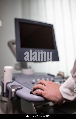 Close up shot of technician operating an ultrasound machine at a clinic. Stock Photo