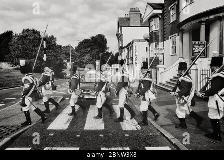 Foot soldiers from the Napoleonic war reenactment period walking across a zebra crossing. Tunbridge Wells, Kent, England, UK. Stock Photo