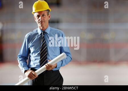 Portrait of a confident mature male architect holding a blueprint at site Stock Photo