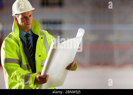 Portrait of a mature male architect looking at a blueprint at site Stock Photo