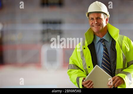 Architect wearing sunglasses and hardhat smiling while standing at