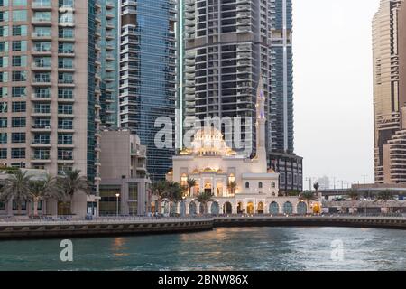 Panoramic view with modern skyscrapers of Dubai Marina and the Mohammed Bin Ahmed Almulla Mosque at sunset, United Arab Emirates Stock Photo