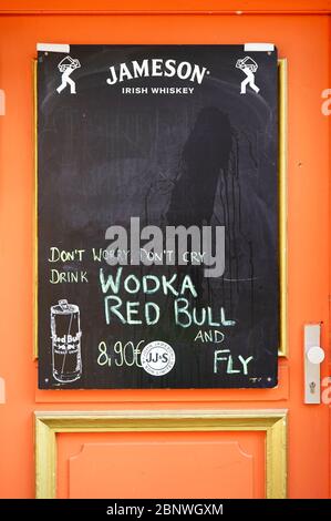 Orange door of a pub in Düsseldorf Old Town with chalk board advertising. Old Town is a popular tourist area with many restaurants and bars. Stock Photo